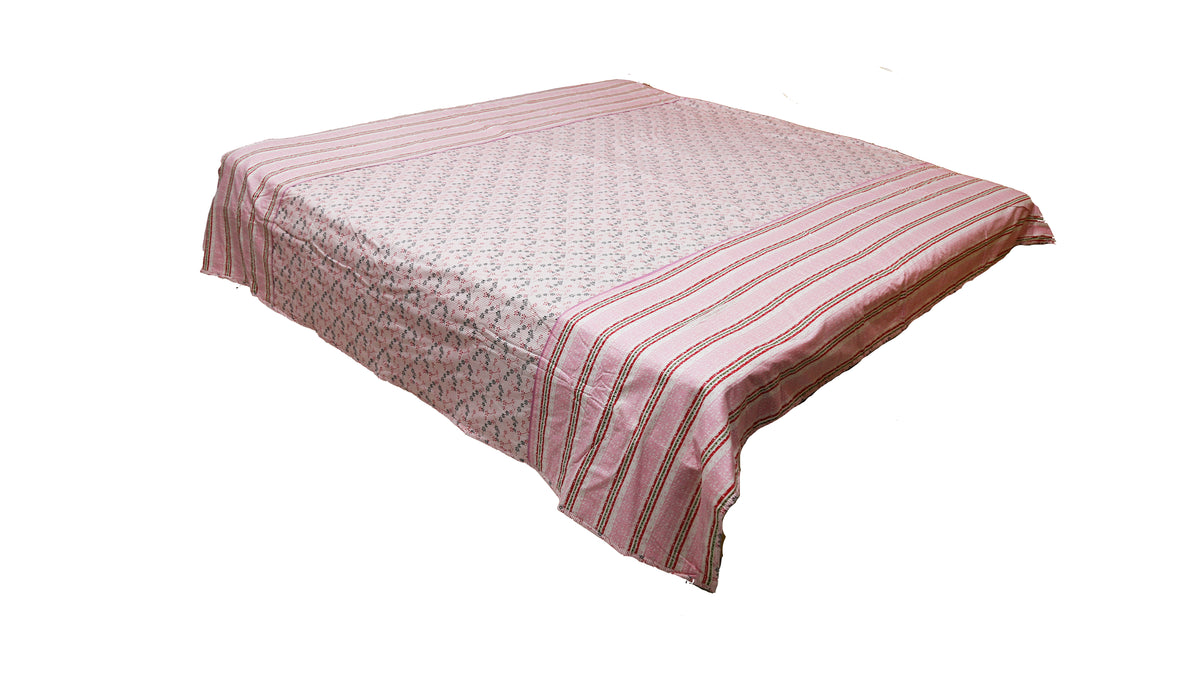 Dusty pink floral dohar draped over a bed, striped border falling down the side