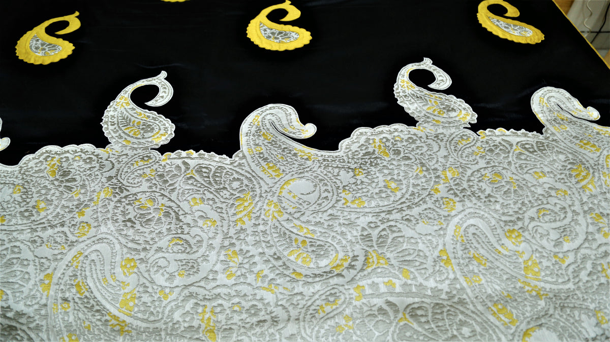 Close-up of ivory brocade paisley border scalloped against black silk