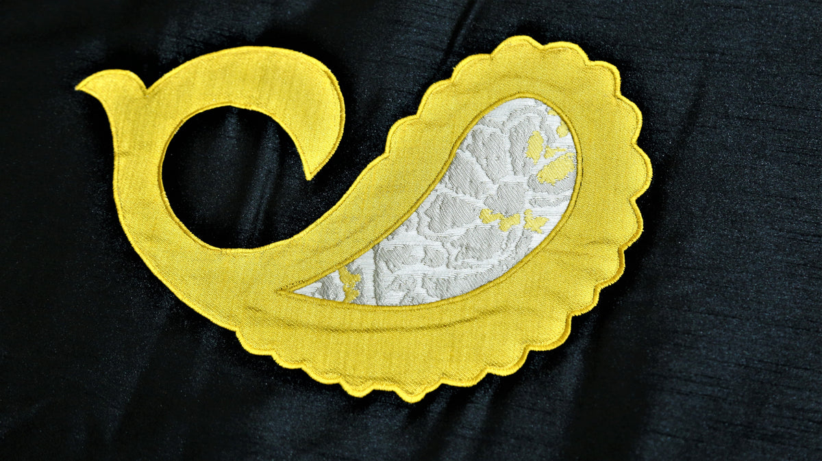 Close-up of yellow satin paisley applique with ivory brocade inlay on black silk