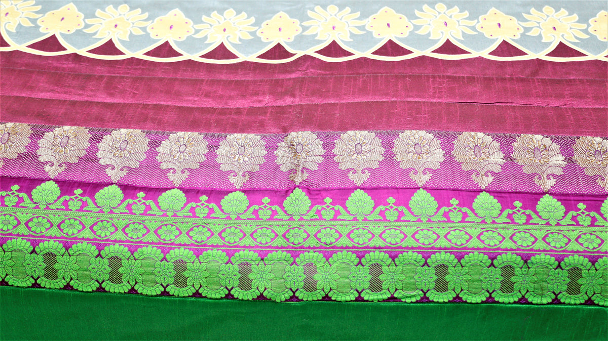 Close-up of green and gold zari brocade bands with cream cutwork on magenta silk