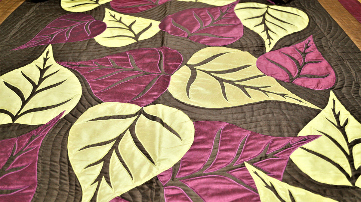 Close-up of cream and aubergine silk leaf applique on quilted brown ground