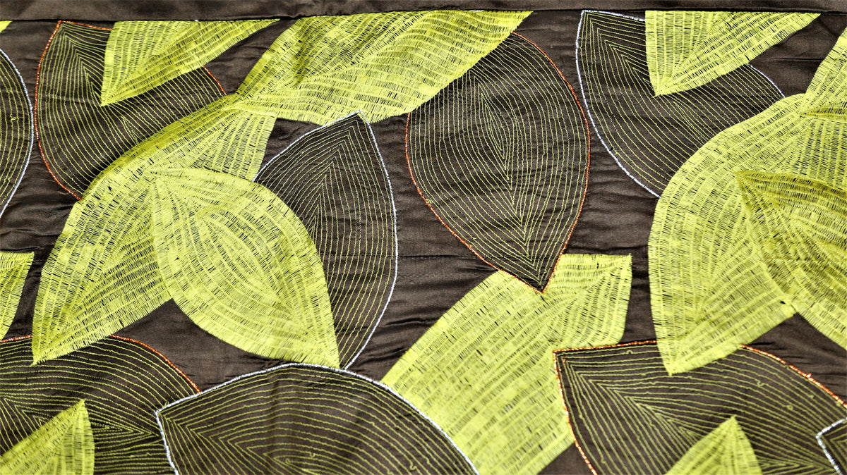 Close up of dark brown fabric embroidered with overlapping lime green leaves