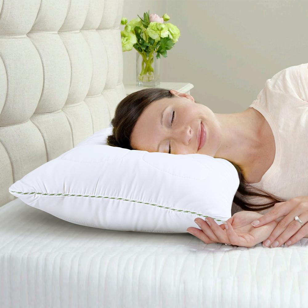 Woman asleep on the white Tencel pillow with its green corded edge, on a made bed