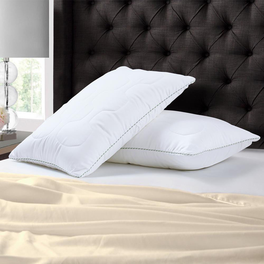Two white quilted Tencel pillows against a dark tufted headboard, grey corded edge