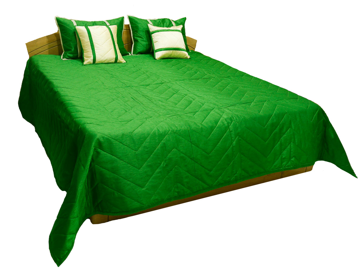 Emerald green quilted bedcover with cream banded cushion covers, angled view