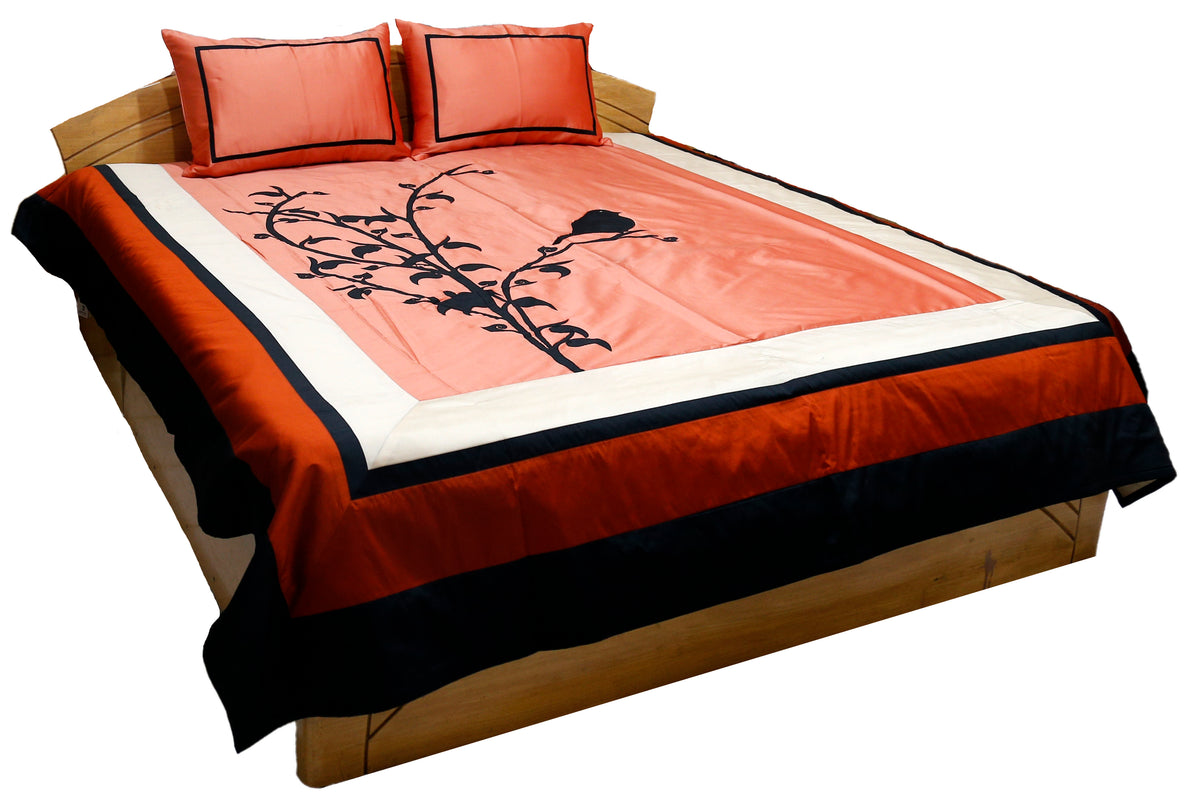 Coral applique bedcover with black bird on branch and coral pillow covers, angled