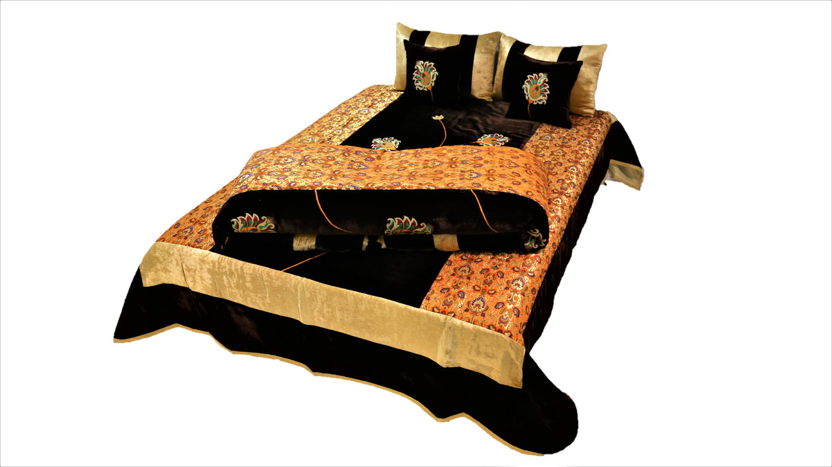 Black and gold flower embroidered velvet wedding set on a double bed, angled view