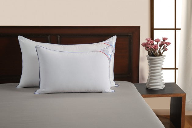 Two Homescapes Cloud pillows on a made bed against a dark wooden headboard